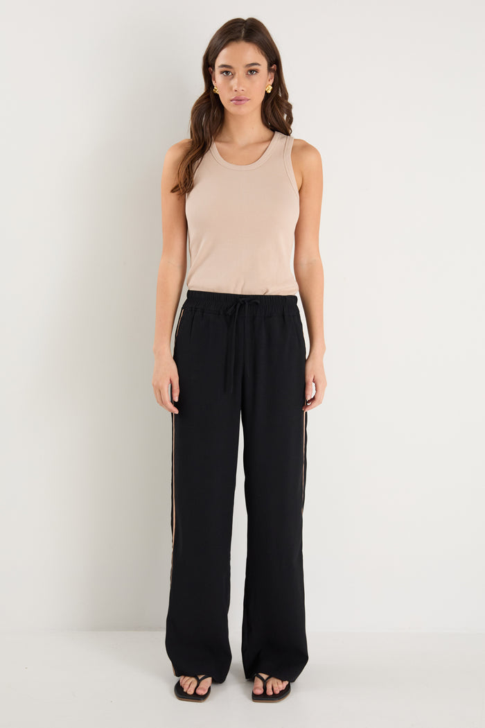 Woman wearing a beige tank top and black pants on a white background
col_pattern