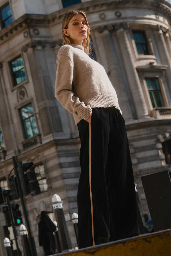 Woman standing on a street corner with a large building in the background