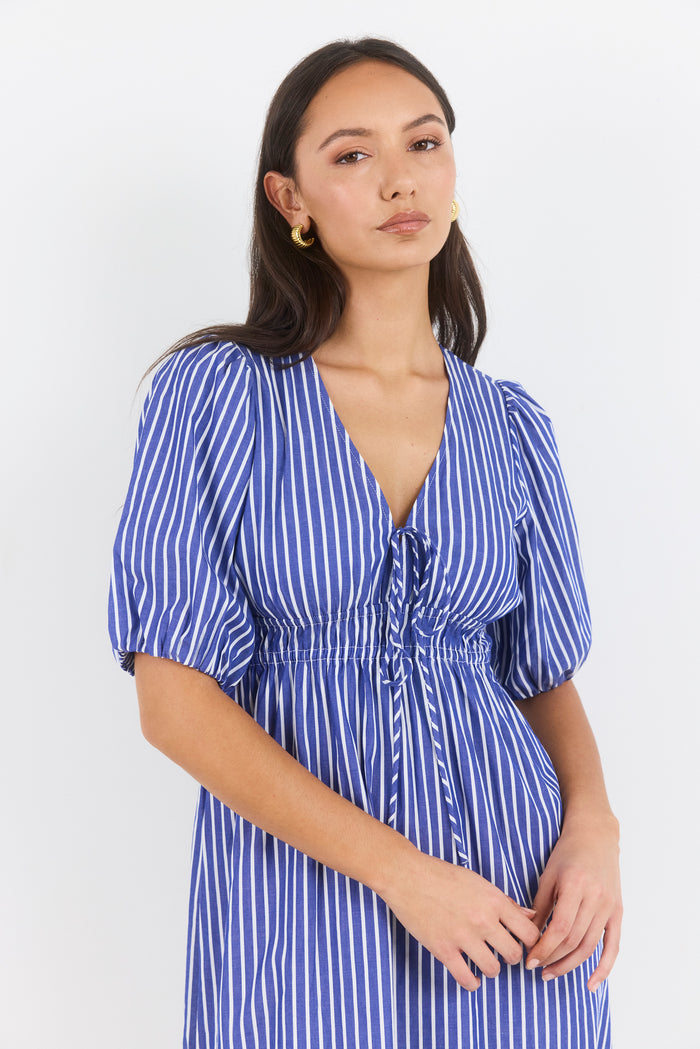 Woman wearing a blue and white striped dress against a white background