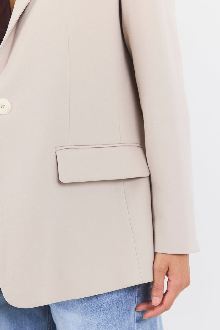 Beige blazer worn by a person on a white background