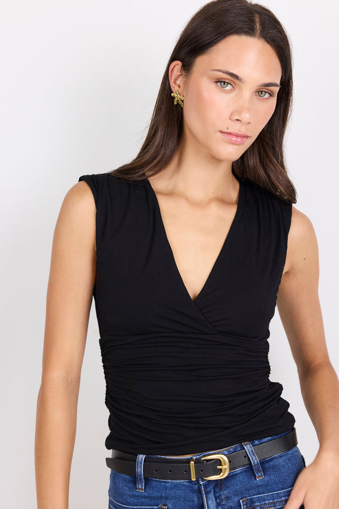 Woman wearing a black sleeveless top and blue jeans on a white background