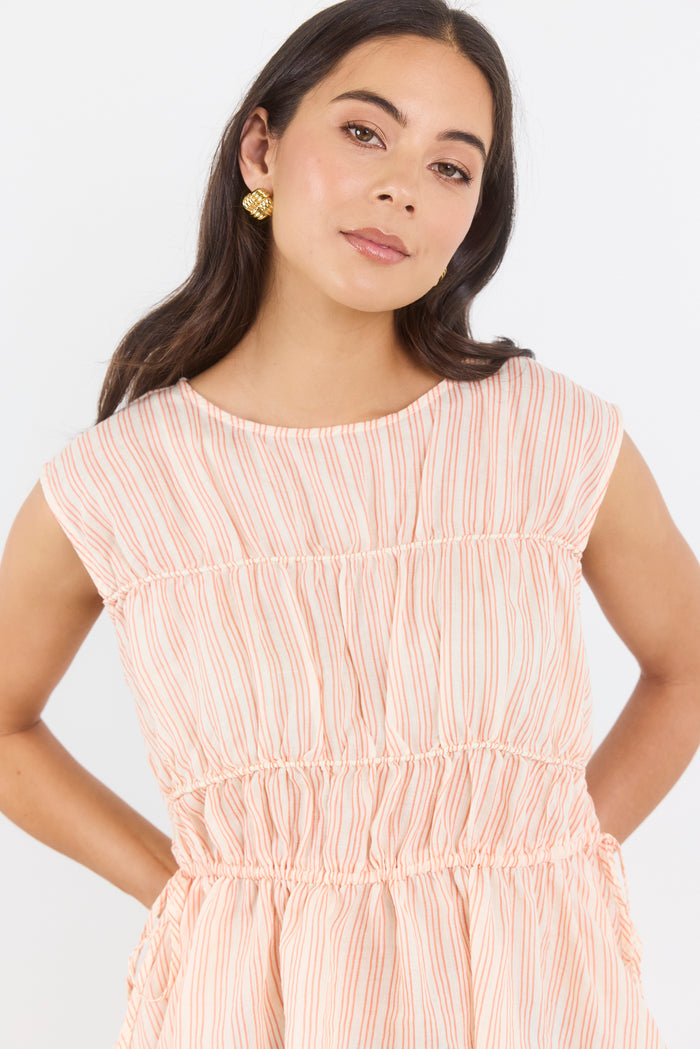 Woman wearing a peach-colored dress with thin white stripes on a white background
col_pattern
