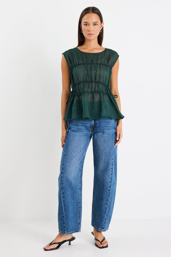 Woman wearing a green top and blue jeans on a white background