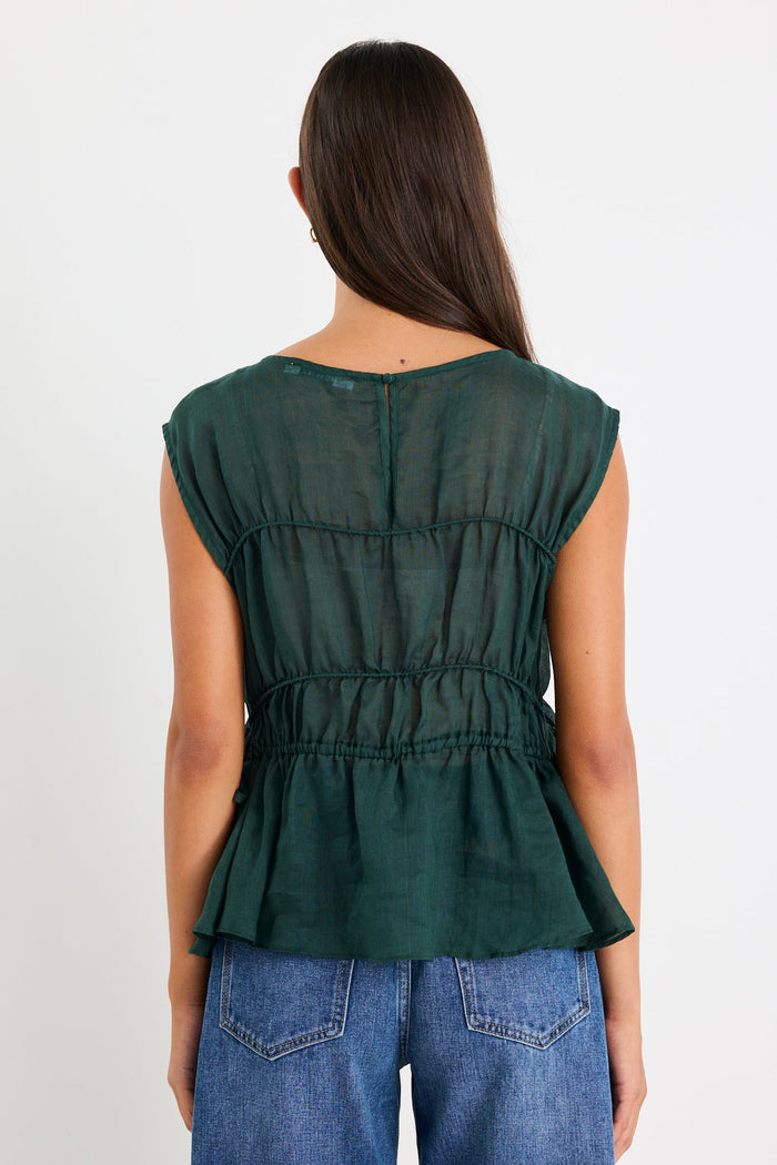 Woman wearing a green sleeveless top and blue jeans on a white background