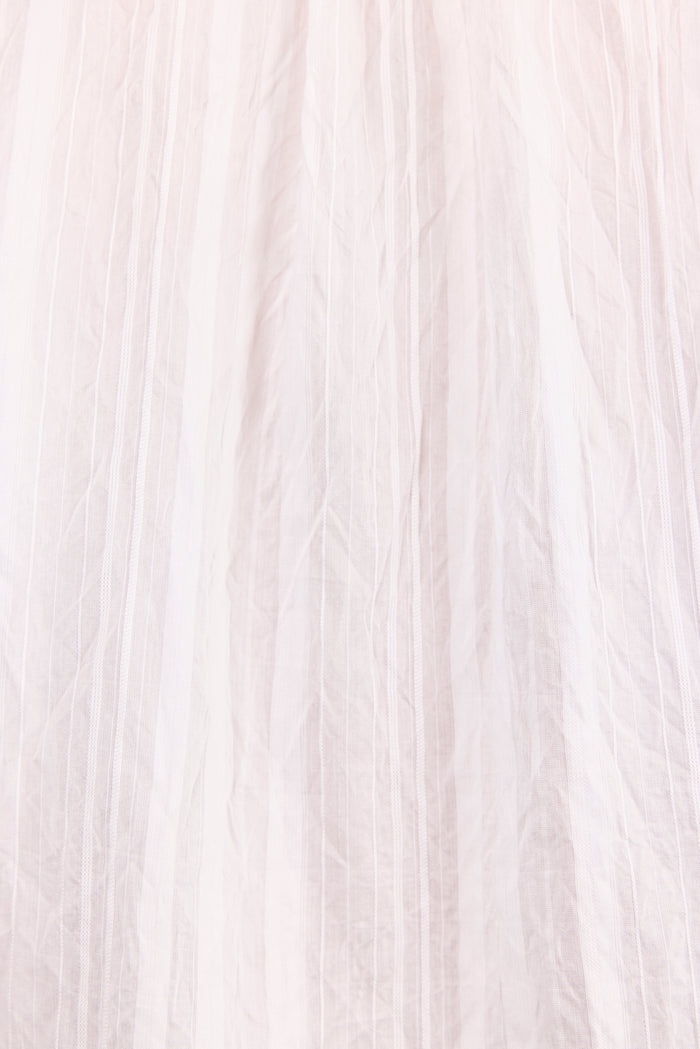 A close-up of a light blush pink pleated fabric, showing the delicate texture and vertical folds.