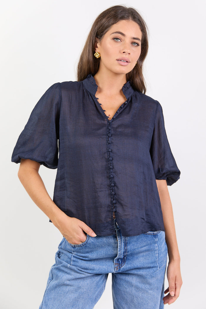 Woman wearing a navy blue blouse and blue jeans on a white background