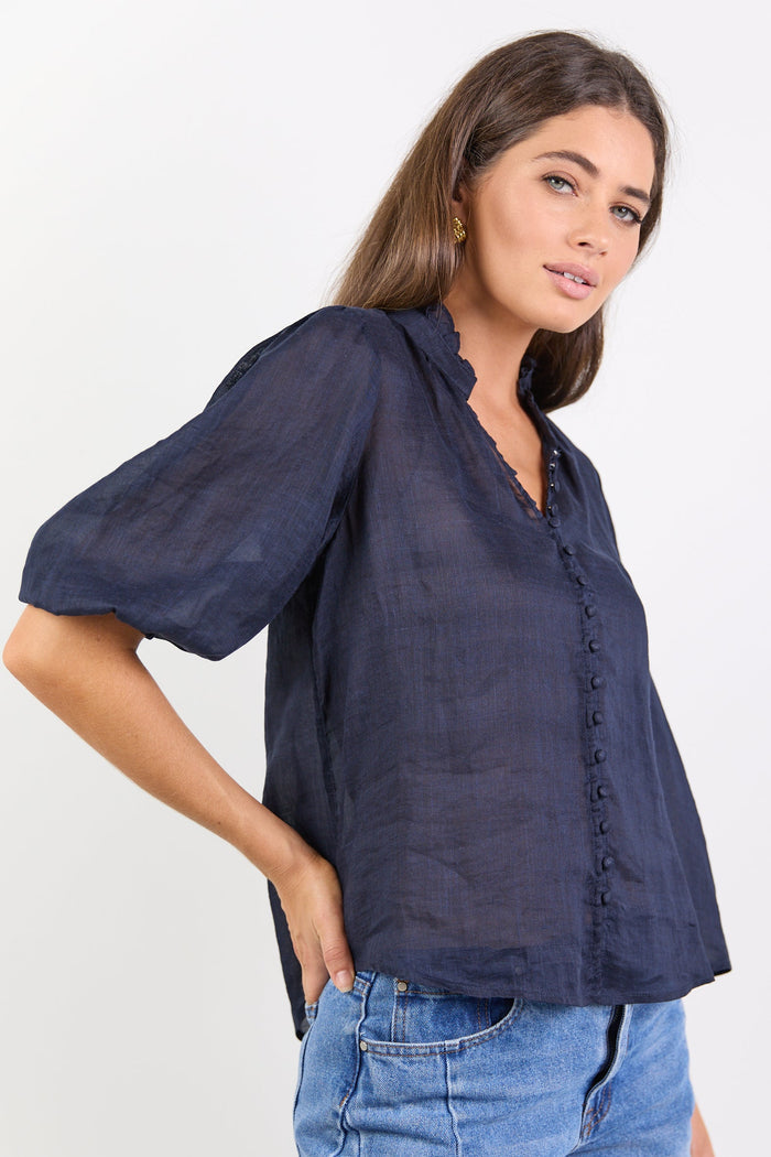Woman wearing a navy blue blouse and blue jeans on a white background