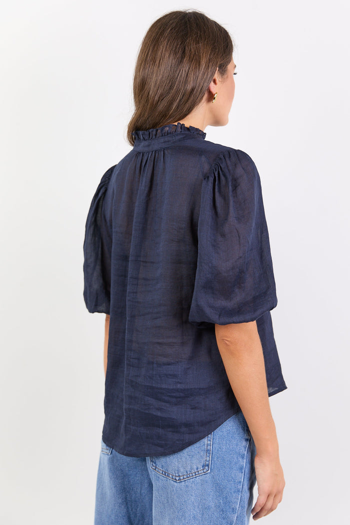Person wearing a navy blue blouse with puffed sleeves on a white background
col_pattern