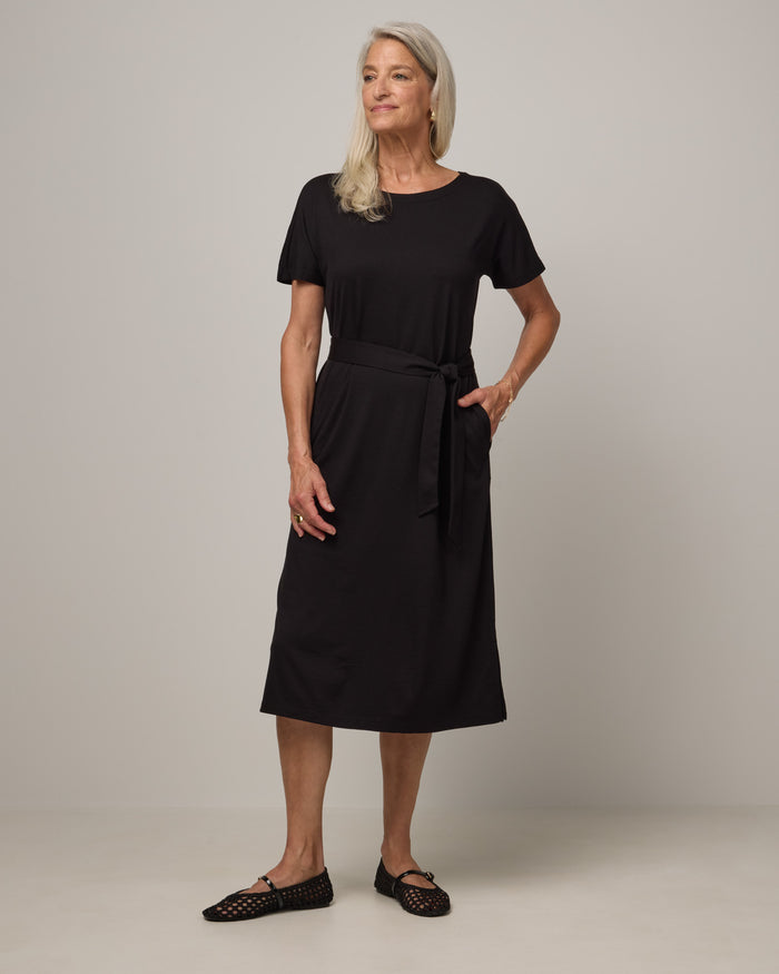 Model wearing Cora Shift Dress in Black. Cora Shift Dress is a merino wool short sleeve, midi shift dress with pockets and removable belt available in sizes XS-3X.