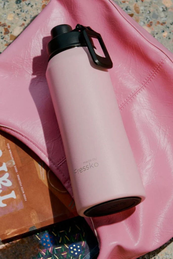 Pink water bottle with black lid on a pink surface