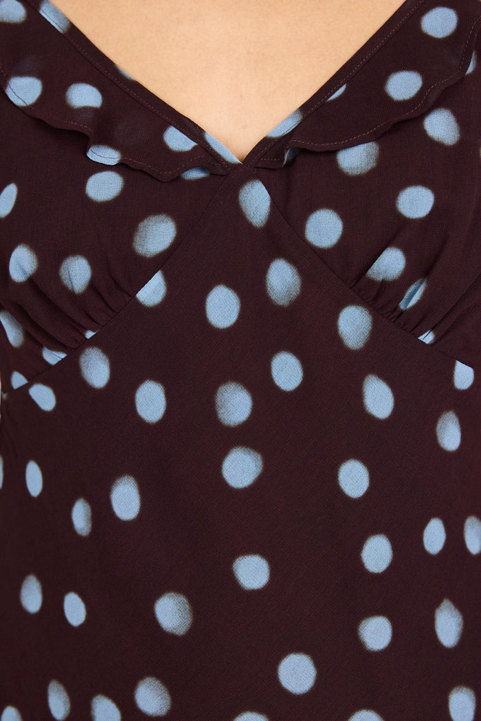 Close-up of a dark brown or very deep burgundy top with light blue polka dots, featuring a ruffled collar and shoulder details.
col_pattern