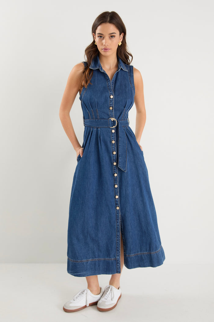 Model wears a sleeveless denim midi dress with white sneakers