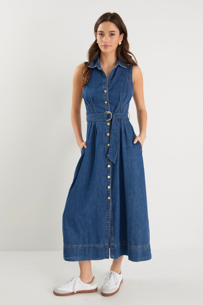 Model wears a sleeveless denim midi dress with white sneakers