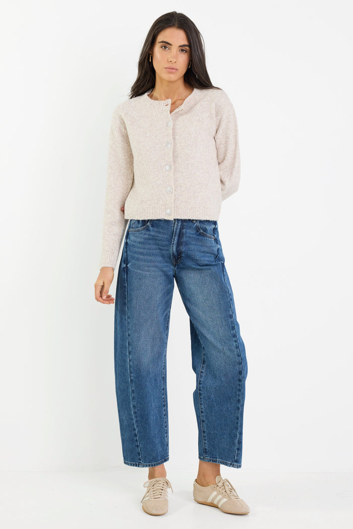 Woman wearing a beige jacket and blue jeans on a white background