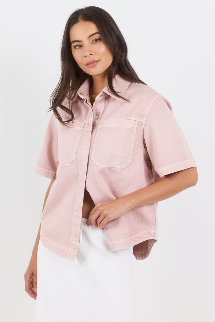 Woman wearing a light pink shirt with short sleeves on a white background
