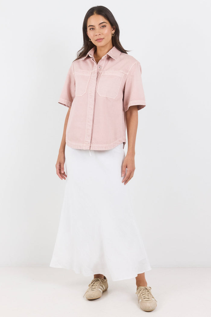 Woman wearing a light pink shirt and white pants on a white background