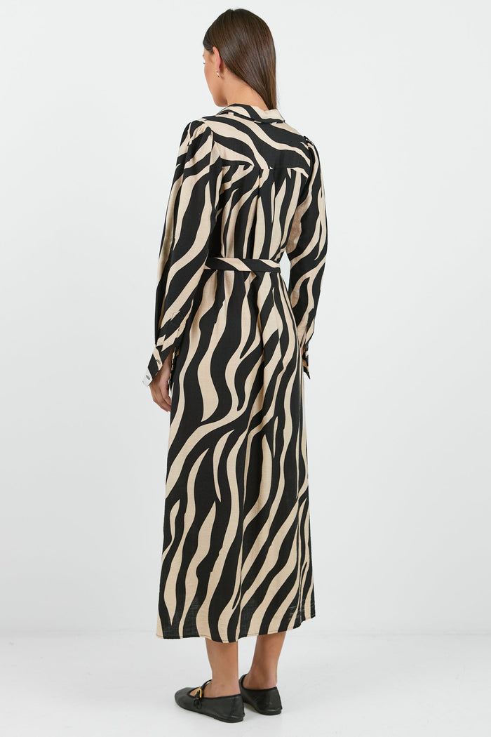 Woman wearing a long zebra print dress on a white background