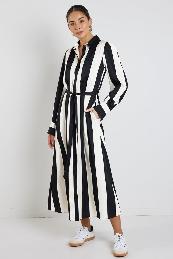 Woman wearing a black and white vertically striped midi dress with long sleeves and tie waist.