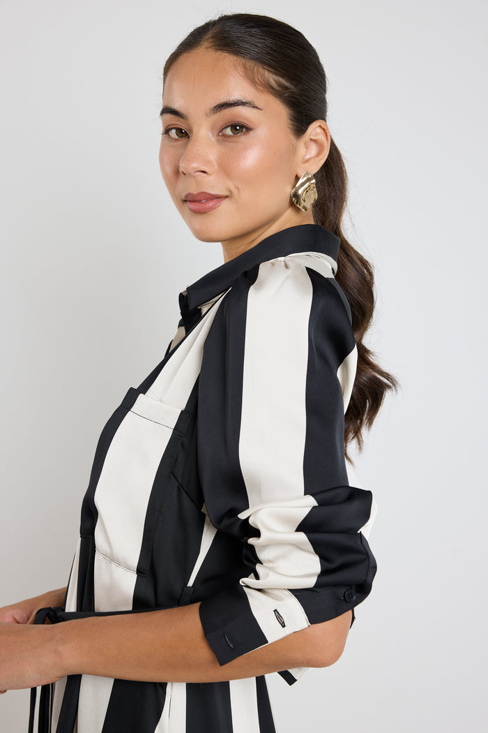 Woman wearing a black and white vertically striped midi dress with long sleeves and tie waist.