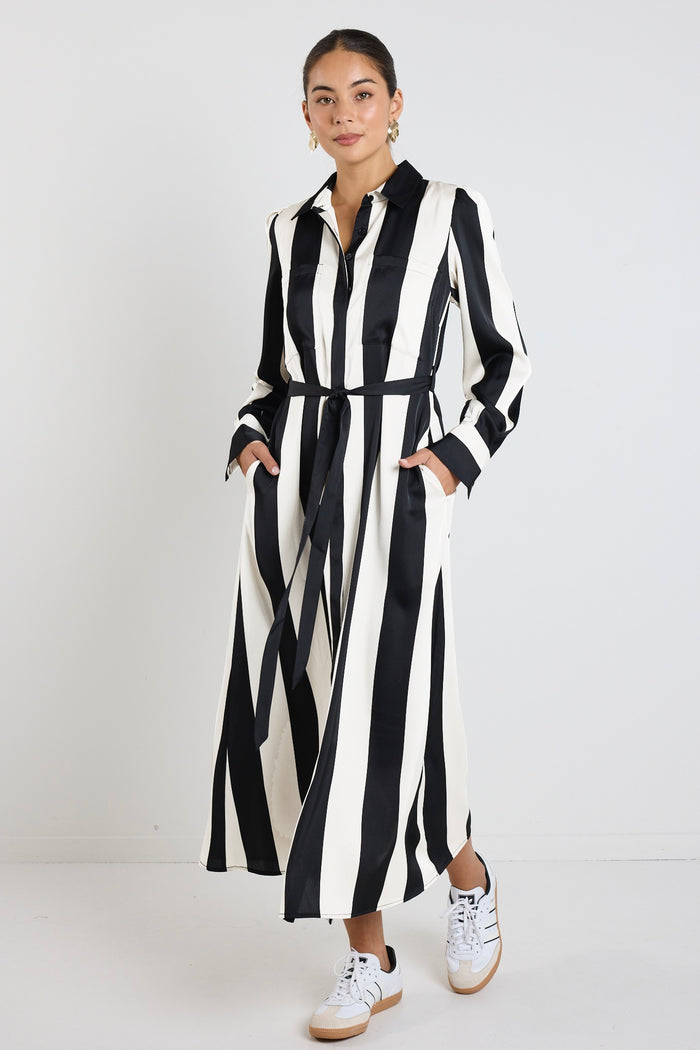 Woman wearing a black and white vertically striped midi dress with long sleeves and tie waist.