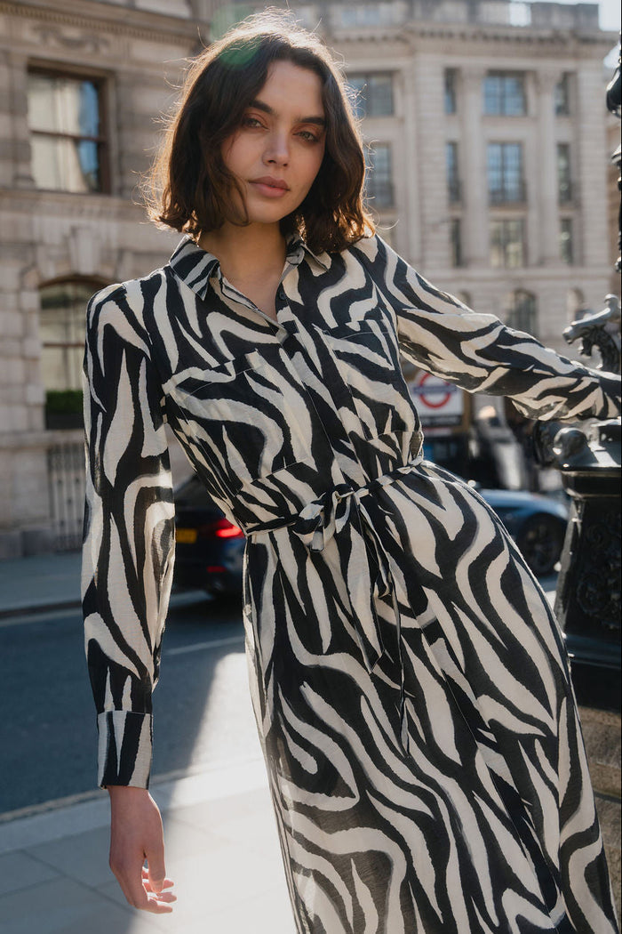 Woman wearing a zebra print dress standing on a city street.