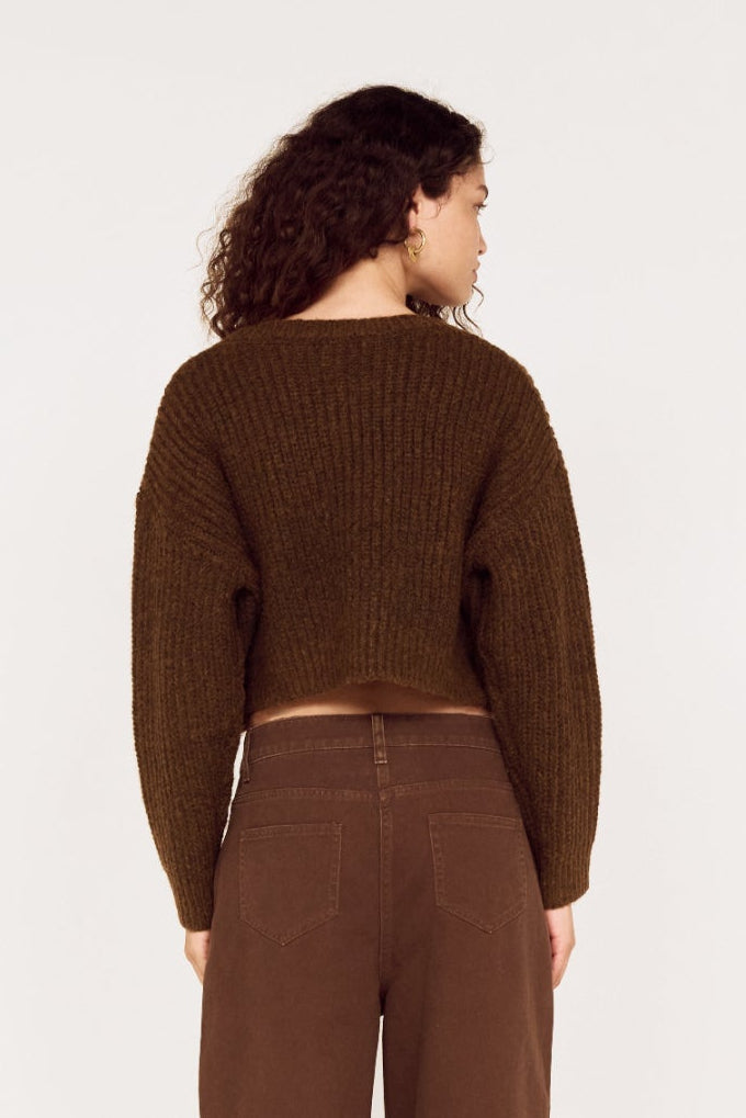 Person wearing a brown ribbed sweater and pants on a white background