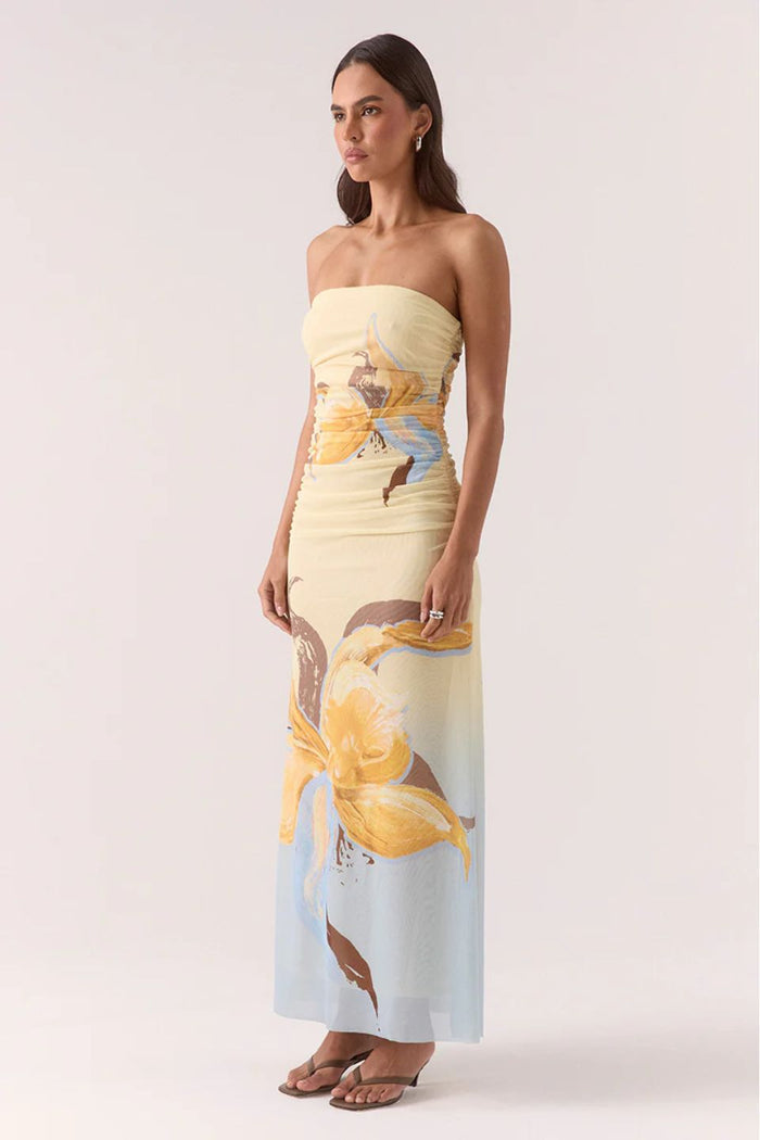 Woman wearing a strapless dress with floral design on a plain background