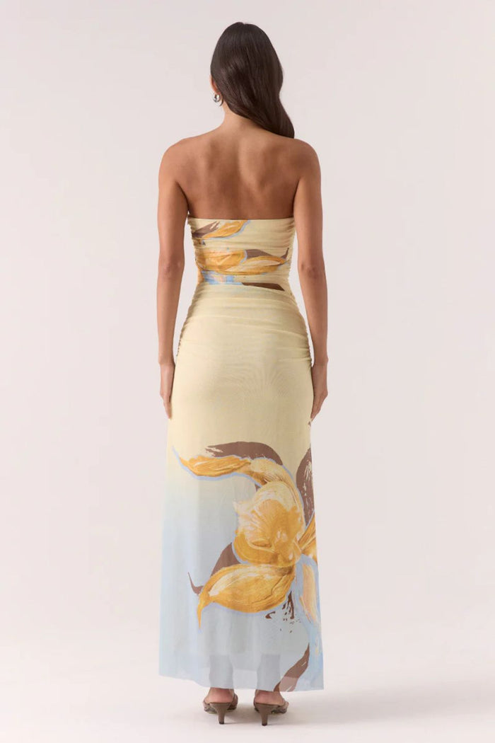 Woman wearing a strapless dress with floral design on a plain background