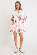 Model wearing a cream mini tiered shirt dress with colourful poppy floral print, puff sleeves and a button front.