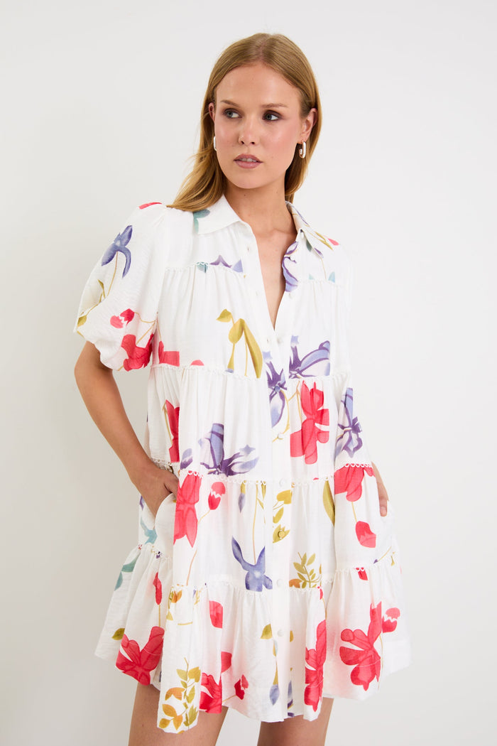 Model wearing a cream mini tiered shirt dress with colourful poppy floral print, puff sleeves and a button front.