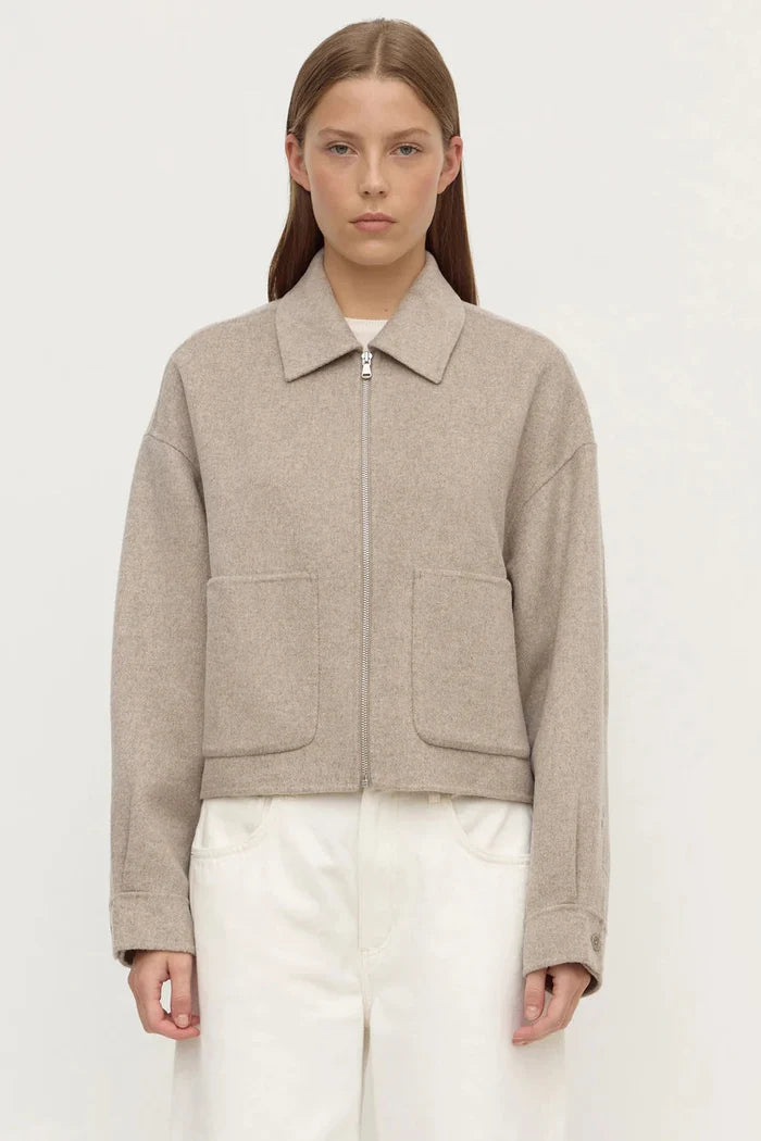 Woman wearing a beige jacket with a plain background