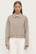 Woman wearing a beige jacket with a plain background