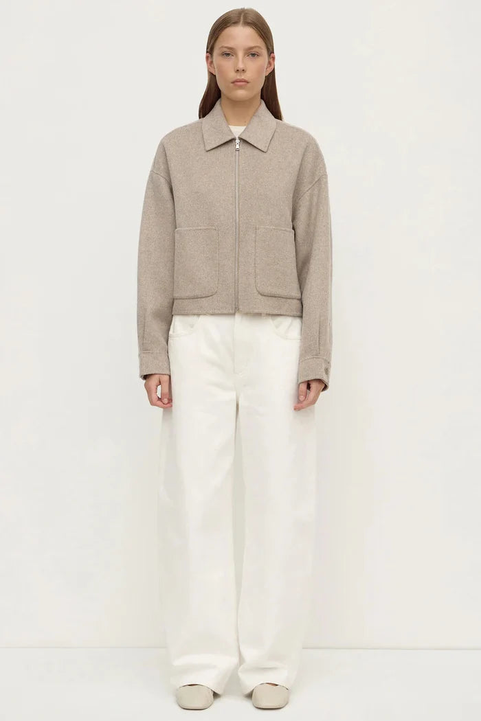 Woman wearing a beige jacket and white pants on a white background