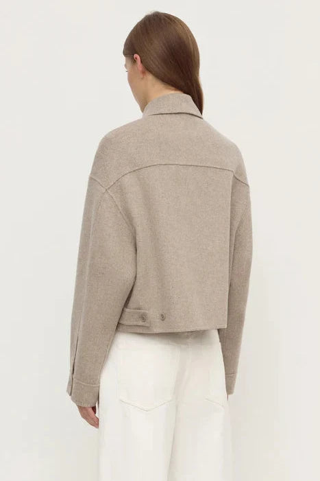 Person wearing a beige jacket on a white background