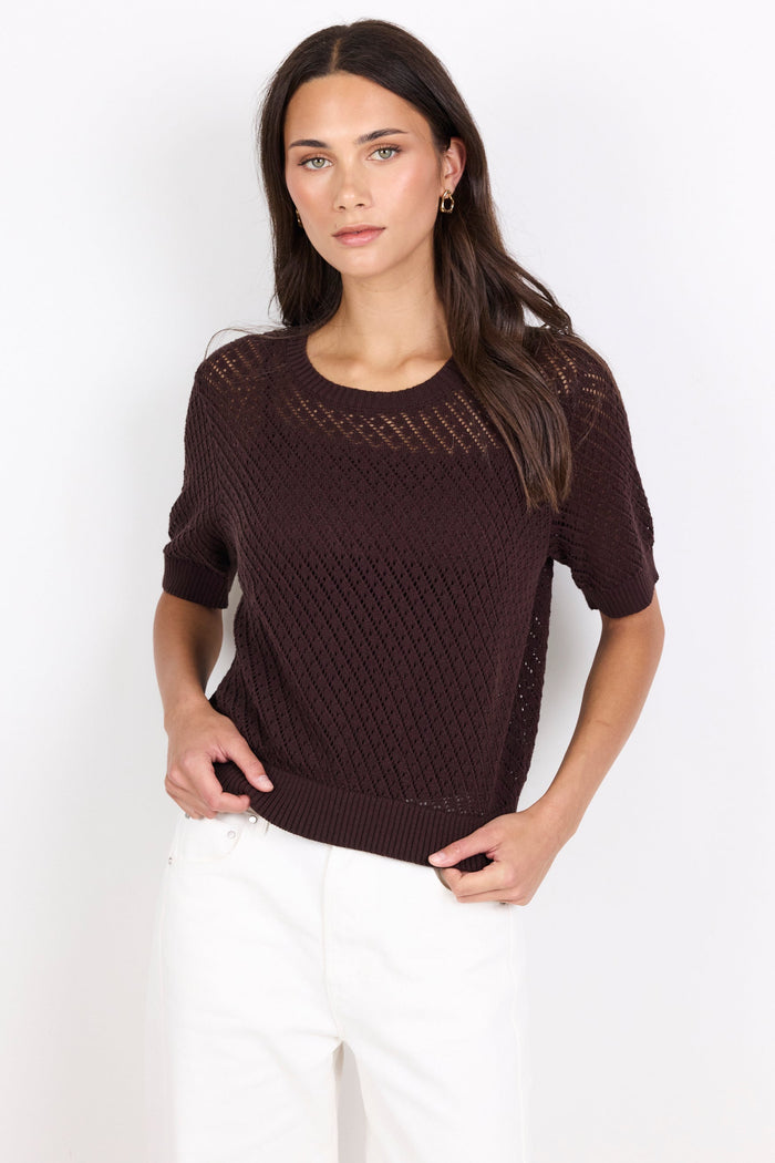 Woman wearing a brown knitted tee against a white background