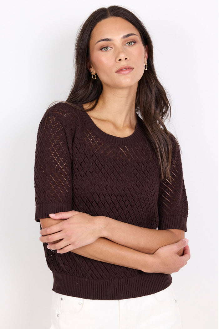 Woman wearing a brown knit sweater against a white background