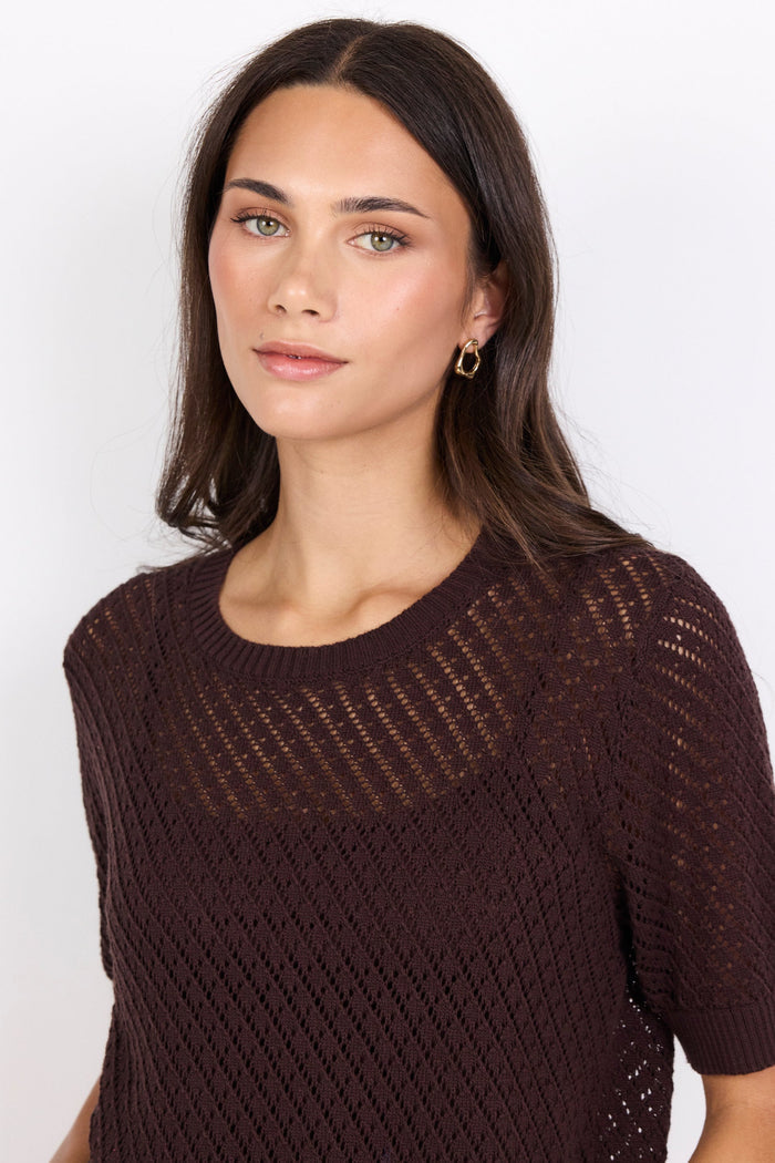 Woman wearing a brown knitted tee against a white background