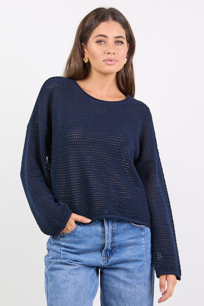 Woman wearing a navy blue sweater and blue jeans on a white background