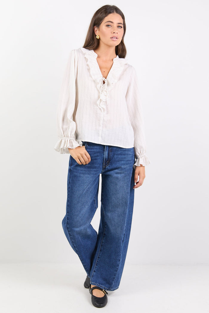 Woman wearing a white blouse and blue jeans on a white background