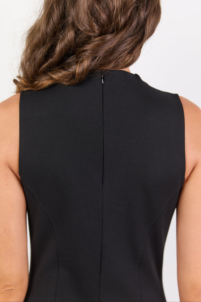Black sleeveless dress worn by a person with a neutral background