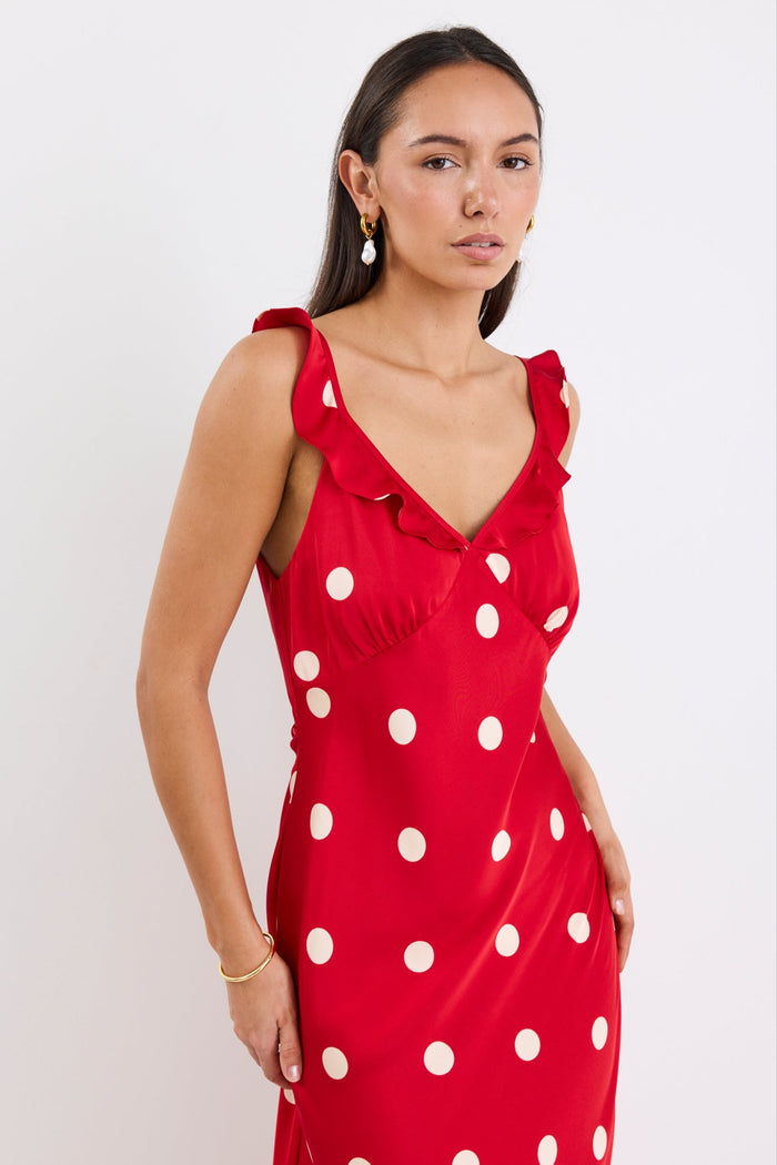 Woman wearing a red satin maxi dress with white polka dots, strappy sleeves, and a flattering bias-cut design.