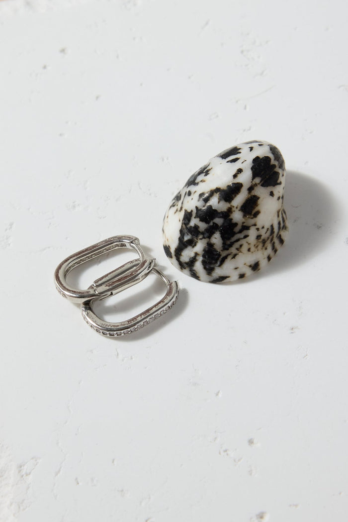 Two rings, one silver and one dalmatian jasper, on a textured white surface.