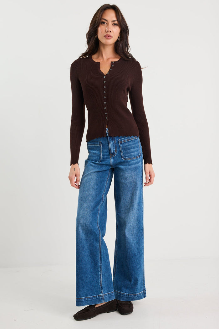 Woman wearing a brown cardigan and blue jeans on a white background