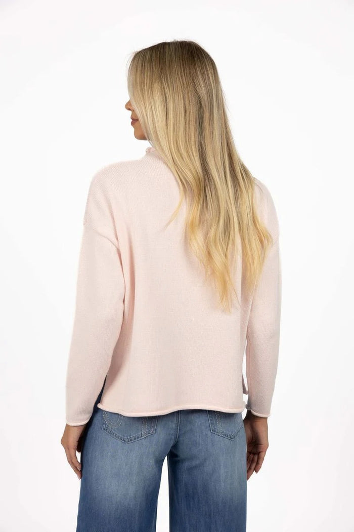 Woman wearing a light pink blouse and blue jeans on a white background