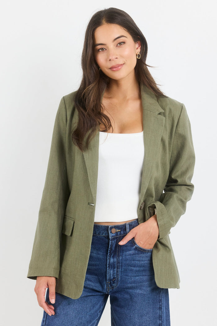 Woman wearing an olive green jacket and blue jeans on a white background