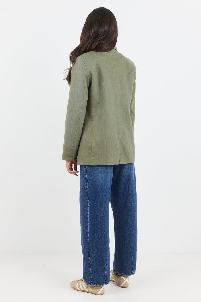 Person wearing a green jacket and blue jeans on a white background