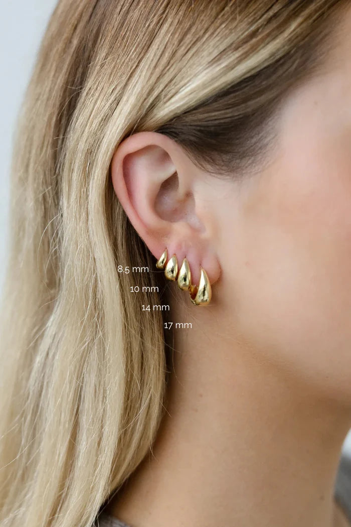 Gold earrings worn by a person with measurements indicated on the earlobe.