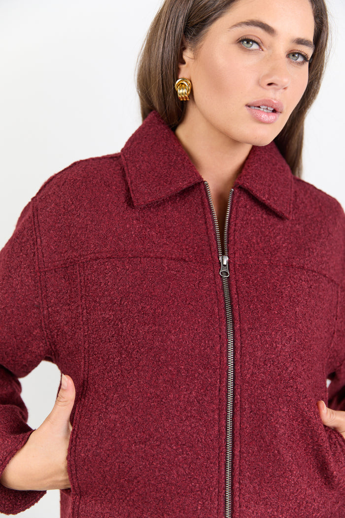 Woman wearing a burgundy jacket with a white background