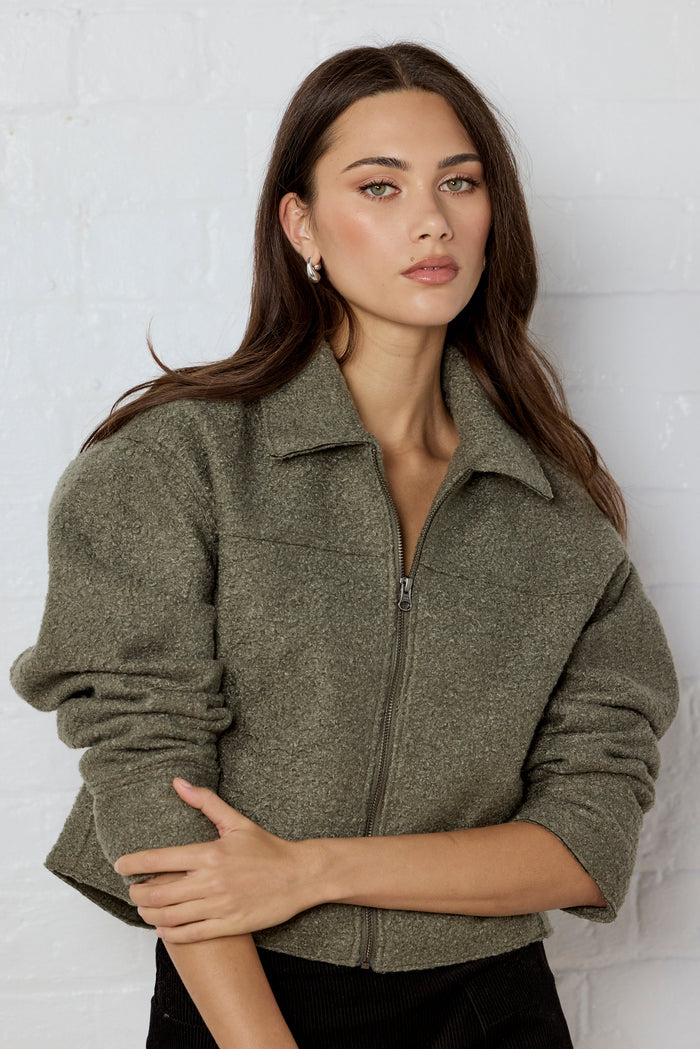 Woman wearing a green jacket against a white background