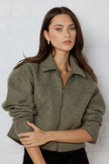 Woman wearing a green jacket against a white background